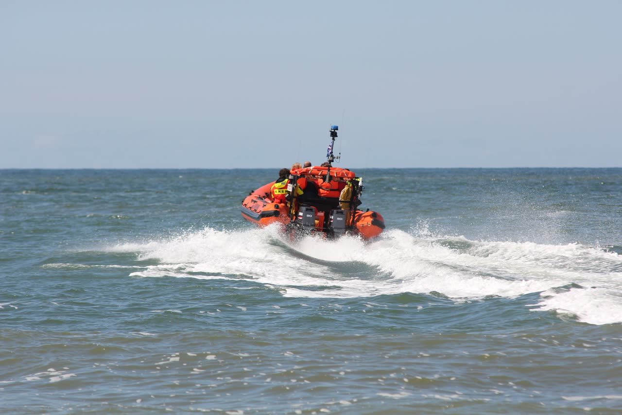 A crewed rescue RHIB under way through breaking surf